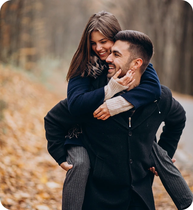 Happy couple with the man giving the woman a piggyback ride in an autumn park